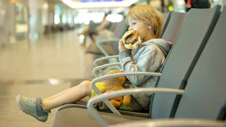 A child eating a huge burger in an airport