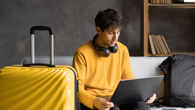 Man with luggage uses laptop