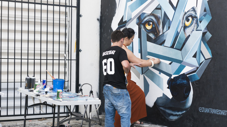 Hialeah public art mural artists working on a blue and white wolf piece