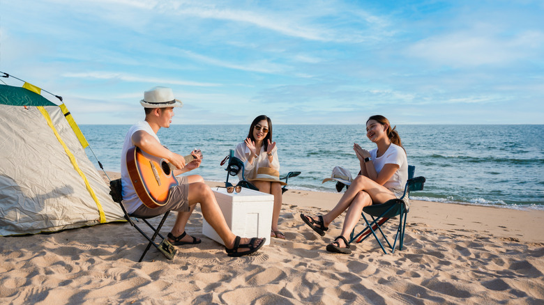 Friends sitting in chairs next to a tent on the beach