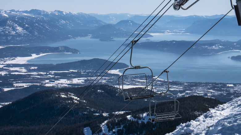 A chair lift in Sandpoint with hills, mountains, and a lake in the far background