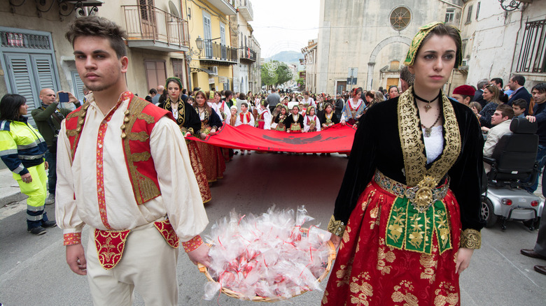 A parade of people in traditional Albanian dress walking through the streets