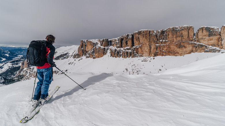 Skier on white snowy slope in front of limestone karst rocks