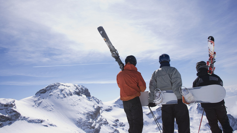 Group of snowboarders and skiers standing on the top of a mountain