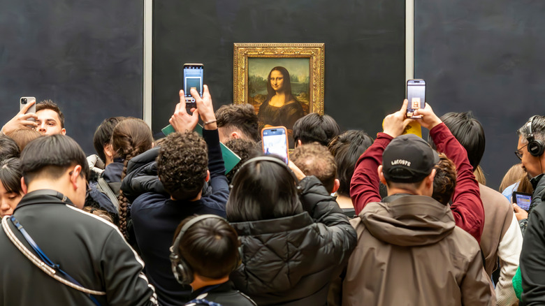 A crowd of people with their phones out obscuring the Mona Lisa