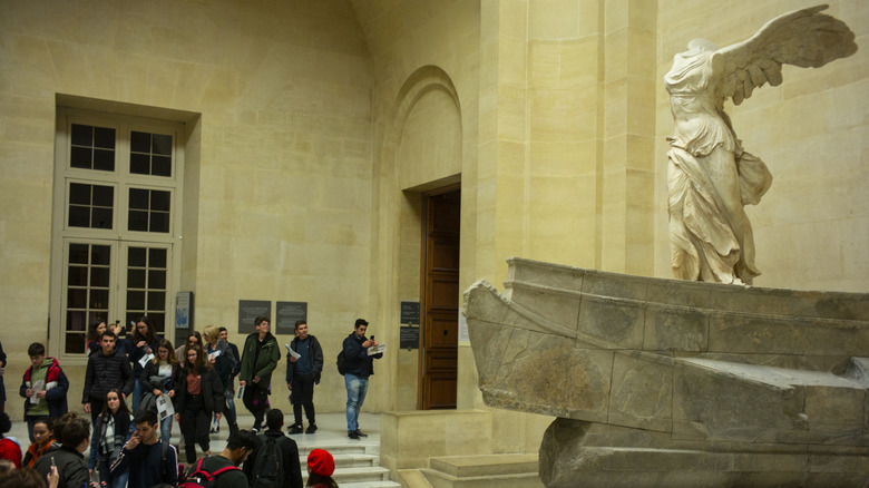 People passing "The Nike of Samothrace" at the Louvre