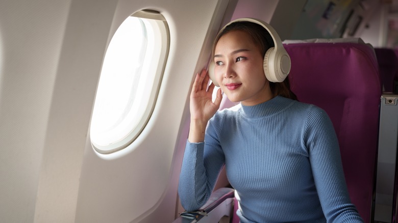 Woman wearing headphones on plane