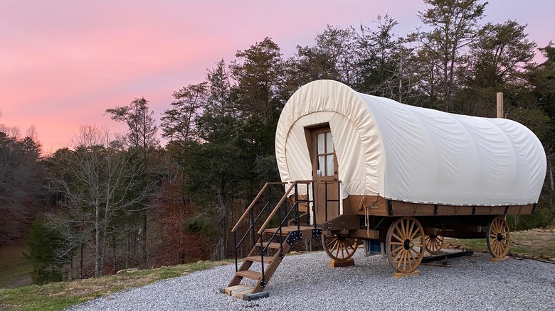 A covered wagon at Smoky Hollow Outdoor Resort with sunset in background