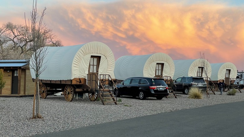 A row of Conestoga wagons at the Verde Ranch RV Resort during sunset