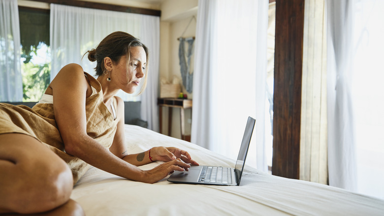 woman on bed looking at laptop screen