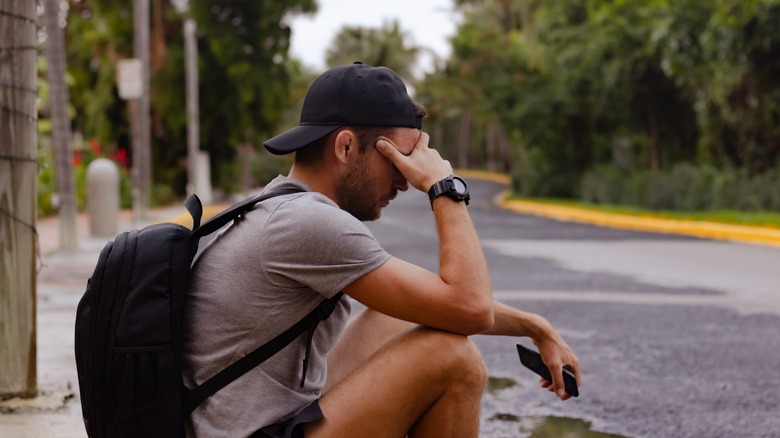 A disappointed man sitting on the street