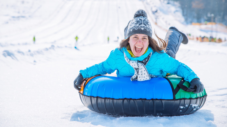 Woman enjoying snow tubing outdoors on a large hill