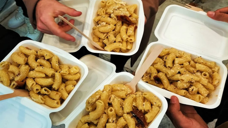 Four people with to-go boxes of carbonara from Pastificio Guerra in Rome