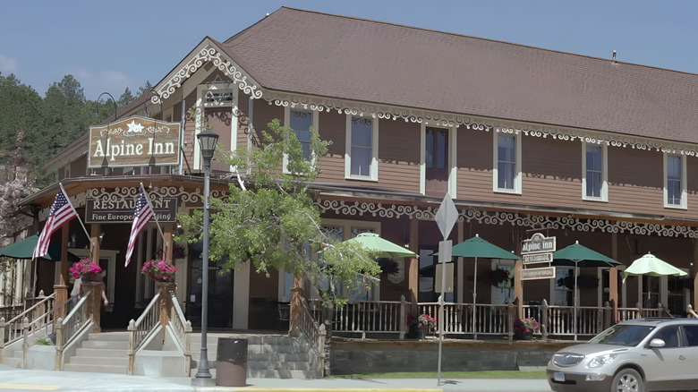 The front of the Alpine Inn, with green umbrellas and a brown roof