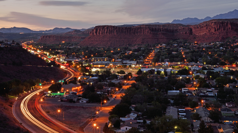 The lit up town of St. George, Utah, at sunset with rock formations in the distance