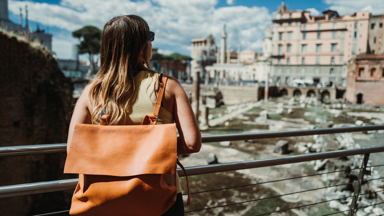 Woman with backpack facing Roman ruins