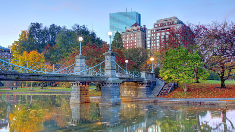 A bridge over water with buildings and trees in the background during the fall in Boston