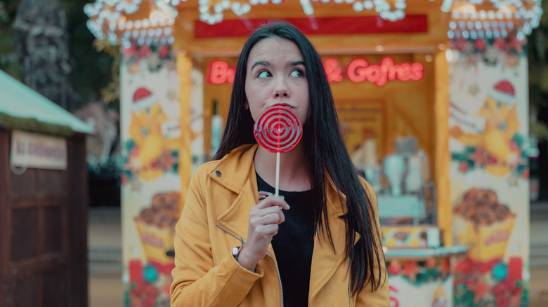 A teenager with a lollipop at a theme park.