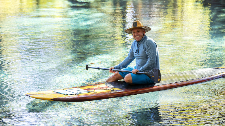 Man paddleboarding in a spring in Florida with crystal-clear water