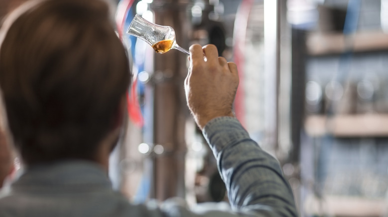 man examining whiskey in distillery