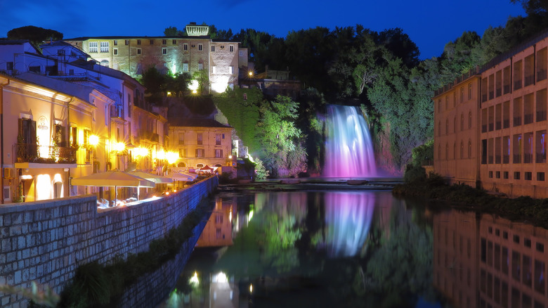 a view of the Liri River at night with the waterfall illuminated by pink lights