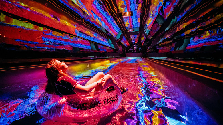 a person on an innertube floating through a colorful tunnel