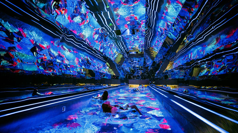 people on innertubes floating in a colorful lazy river tunnel