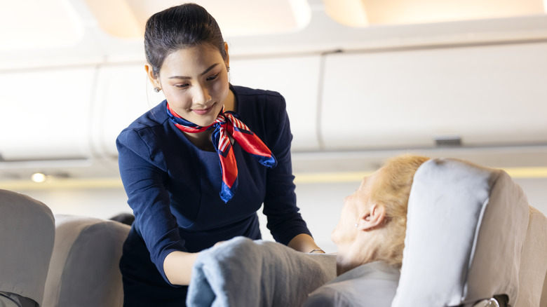 Flight attendant giving blanket to passenger