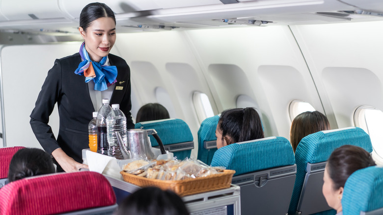 Flight attendant pushing food cart down the aisle