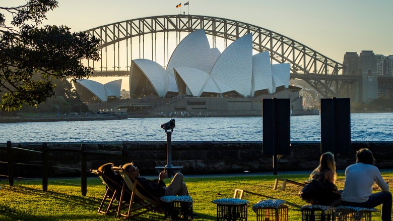 People lounging in the grass with the Sydney Opera House in front