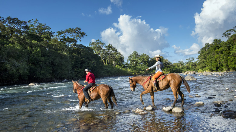 Couple crossing a river on horseback in Costa Rica