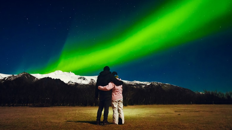 Couple holding each other below the Northern Lights