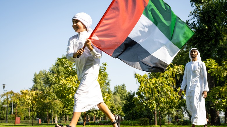 Boy in traditional attire flying Kuwaiti flag