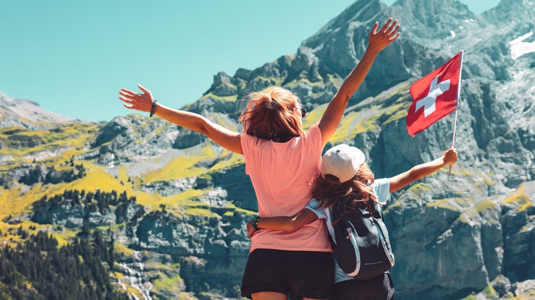 Woman raising arms with child holding Swiss flag