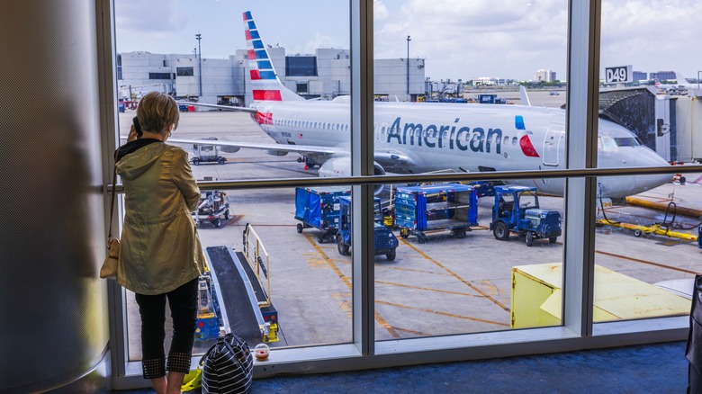 Woman with bag looking at airplane at Miami International Airport