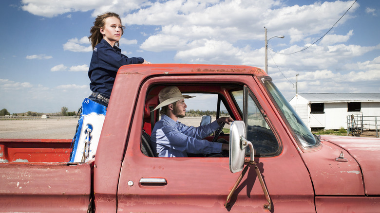 Cowboy and cowgirl traveling in red pick up truck