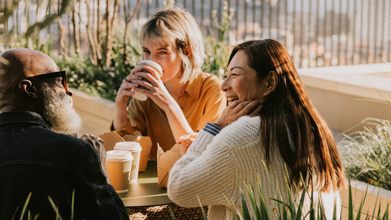 Three people drinking coffee and laughing