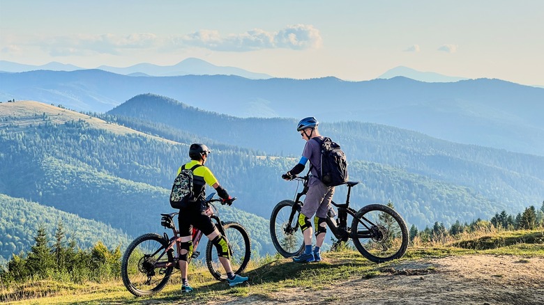 Two people riding e-bikes through hilly landscape