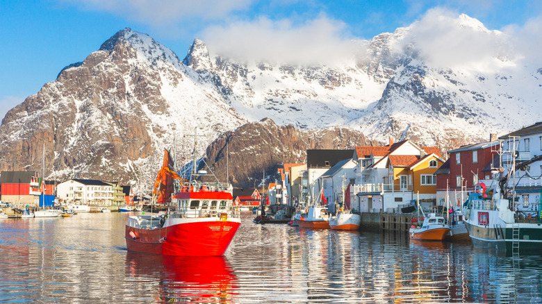 A bay in the Lofoten Islands, with snowy mountains in the background and a red boat in the front