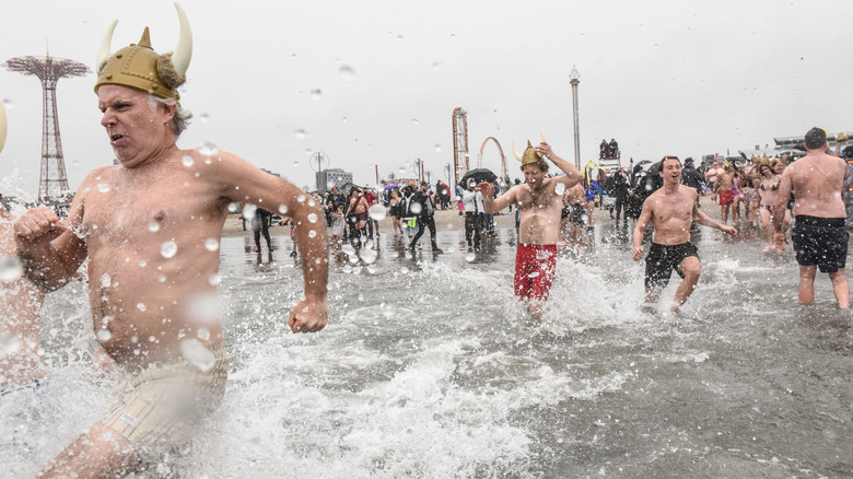 People at Coney Island in New York running into the water for the annual polar plunge with bathing suits and Viking helmets