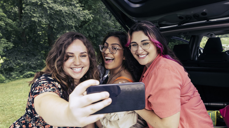 Three women taking selfie from back of car