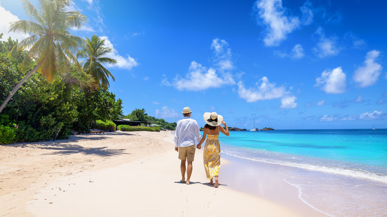 Couple walking along sunny beach in Antigua