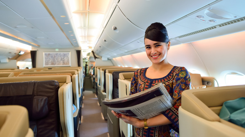 Singapore Airlines flight attendant holds newspapers on plane