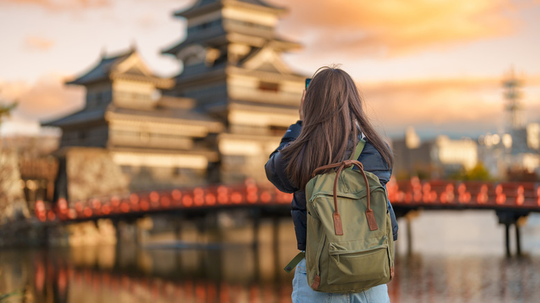 Solo female traveler taking photo of temple in Japan