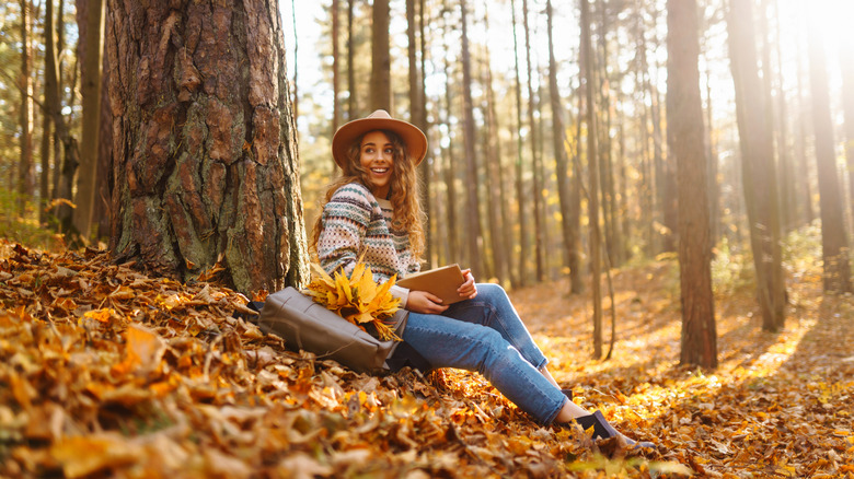 Woman sitting on autumn leaves with a book