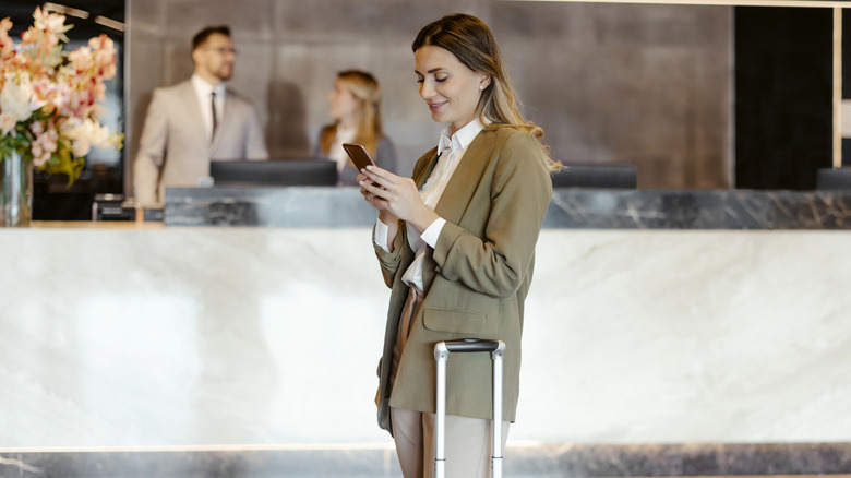 woman with cellphone checking into hotel