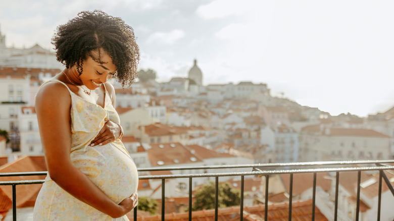 Woman holding belly with city in background