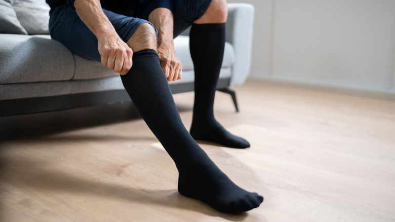 A person puting on black compression socks at home