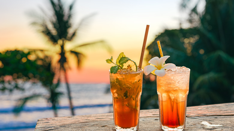 Two orange drinks overlooking a Jamaican beach sunset