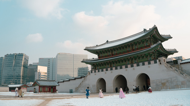 People standing in front of Gyeongbokgung Palace in the snow